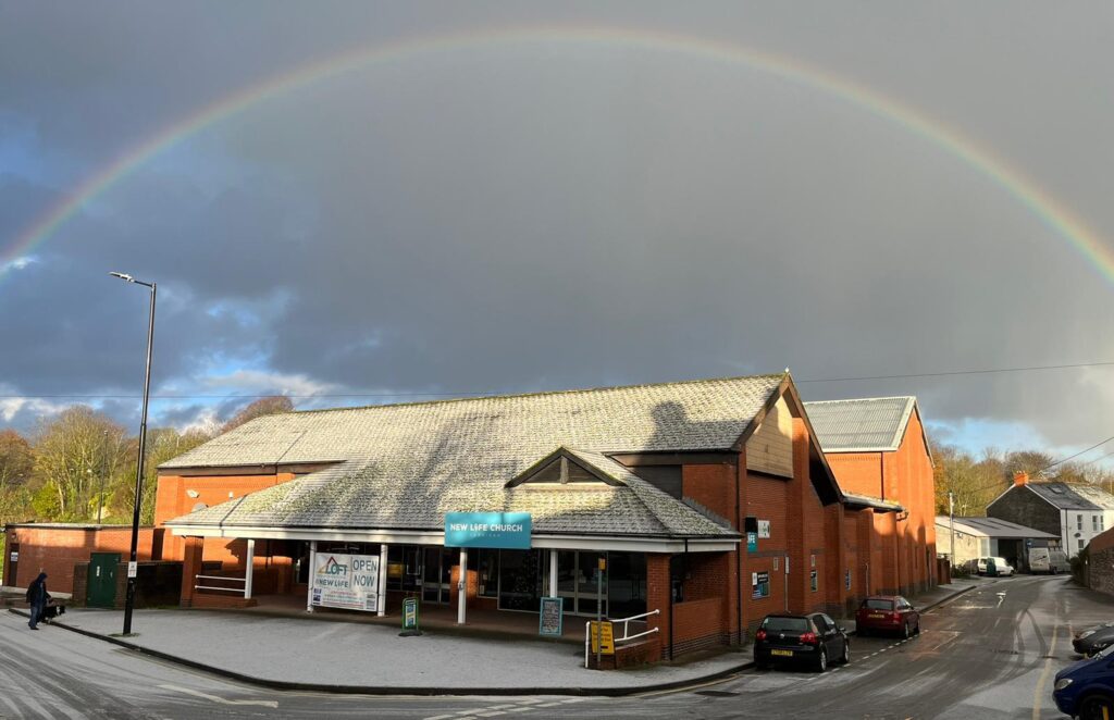 A photograph of a rainbow over the New Lift Church building